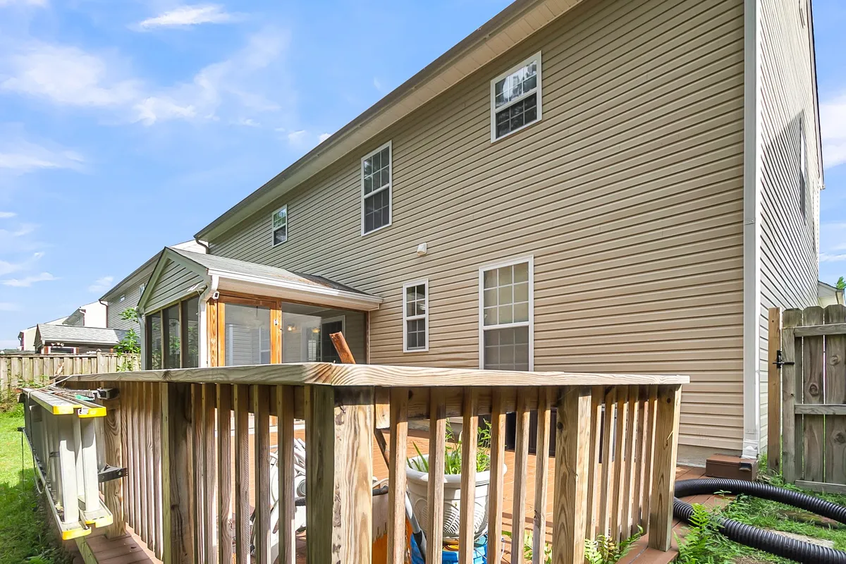 A view of a deck area with a glass-enclosed porch surrounded by greenery, inviting guests to relax outdoors and enjoy the natural setting. The environment is cozy and ideal for group entertaining.