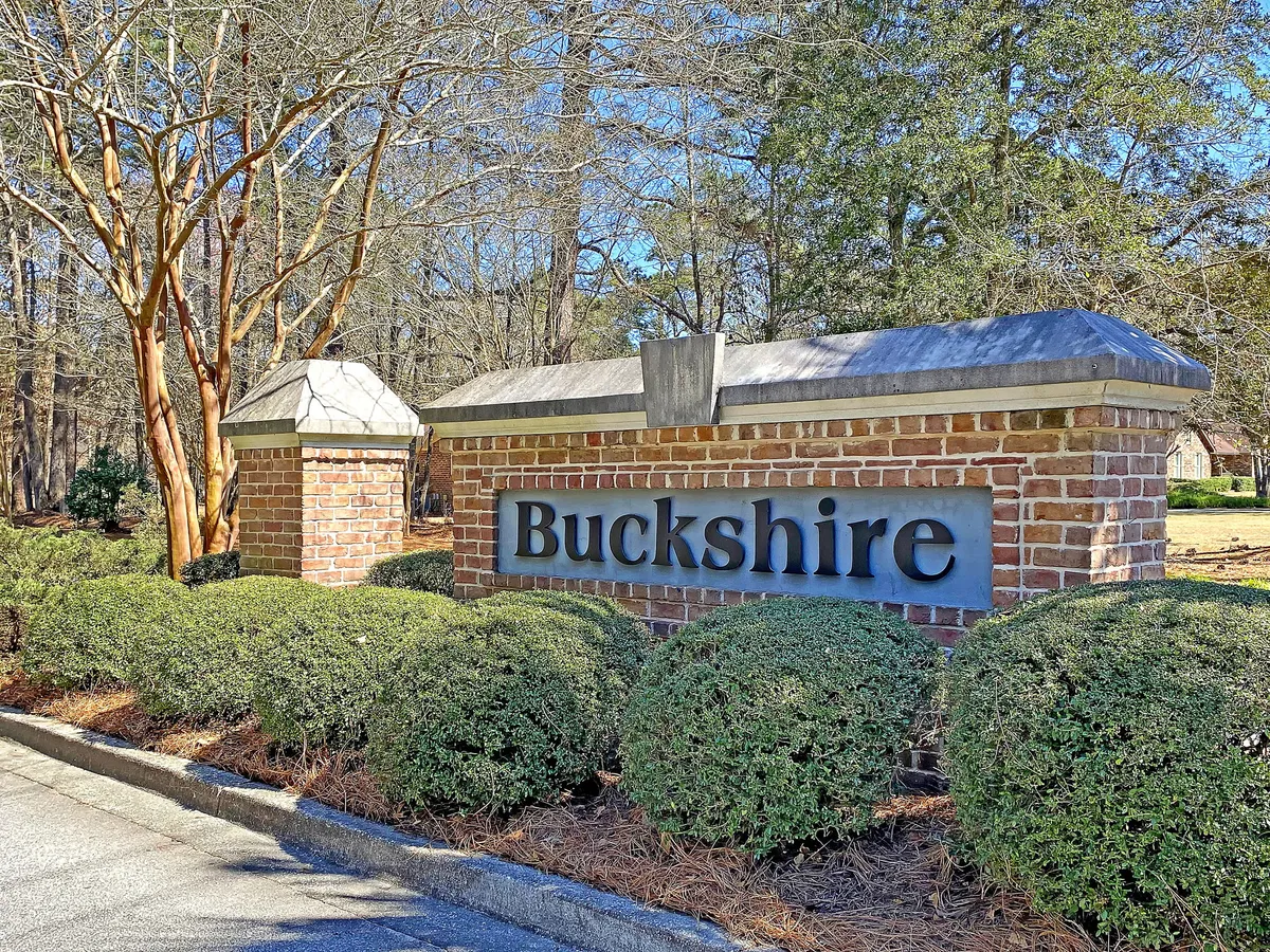 This image features the Buckshire community sign surrounded by landscaped bushes and trees, highlighting the broader neighborhood and its communal feel. The setting suggests walkability and access to local amenities, aligning with the narrative of exploring Summerville's business centers, shopping, and dining.