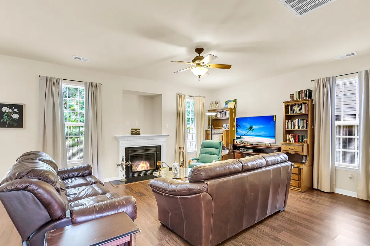 A cozy living space featuring a central fireplace, television, bookshelf, and ample seating. The room invites relaxation and socializing, creating a comfortable gathering spot for all ages.