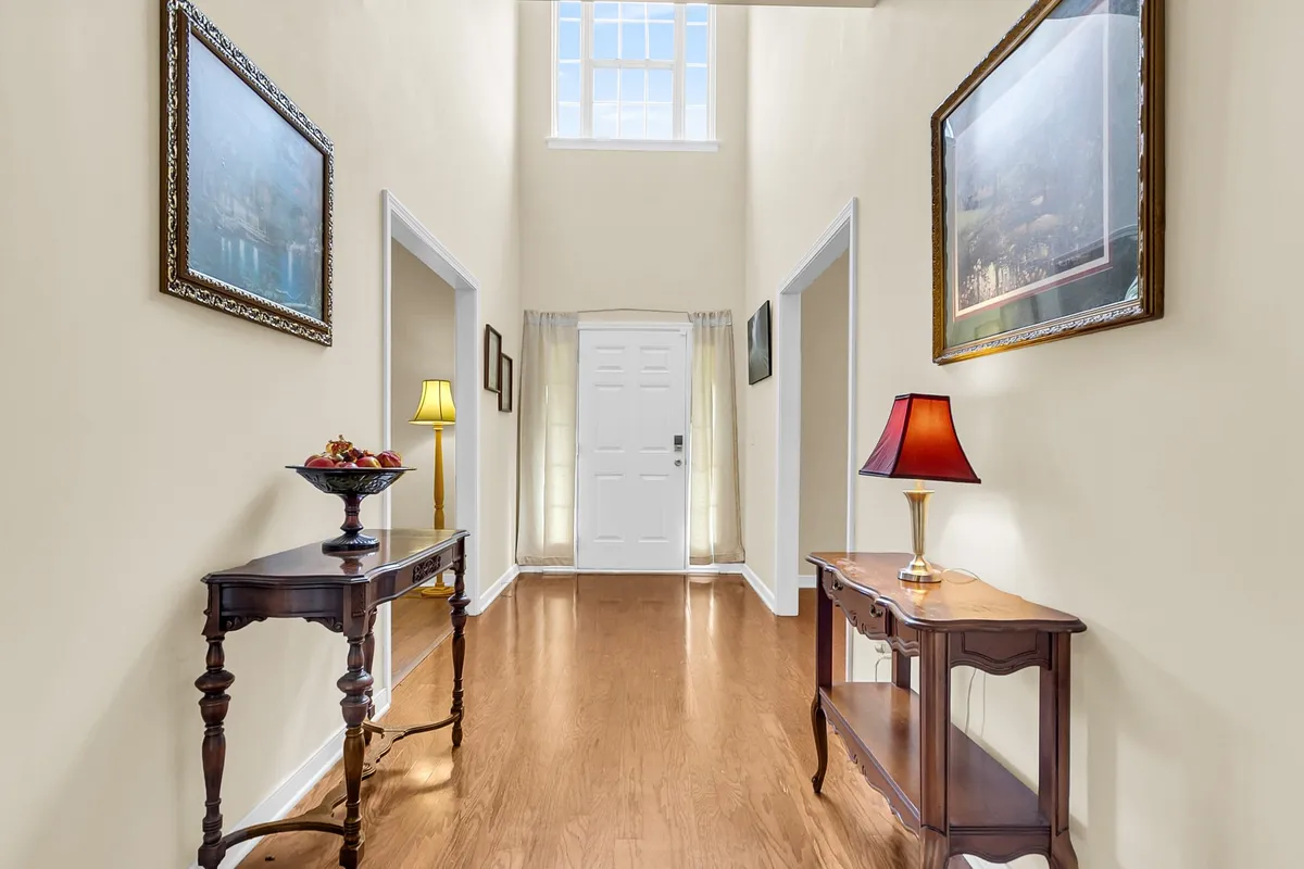 This image captures the front door area from inside the home. A decorative lamp and wall art adorn the space, and a console table sits against the wall, creating a well-organized, inviting entryway. The view highlights a transitional area where guests and residents would enter and start to settle in.