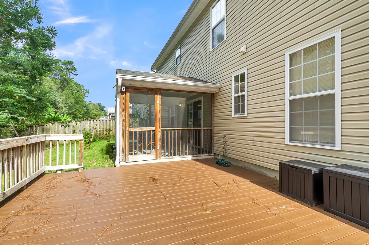 A deck area with a screened porch looking onto lush backyard greenery, offering space for barbecues, family gatherings, and outdoor relaxation.