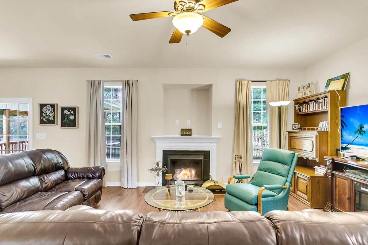 A comfortable living room setup with sofas arranged around a coffee table and facing a fireplace and television. The bookshelf adds a touch of homeliness, and the layout encourages conversation, relaxation, and entertainment.